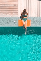 woman lying beside swimming pool during daytime