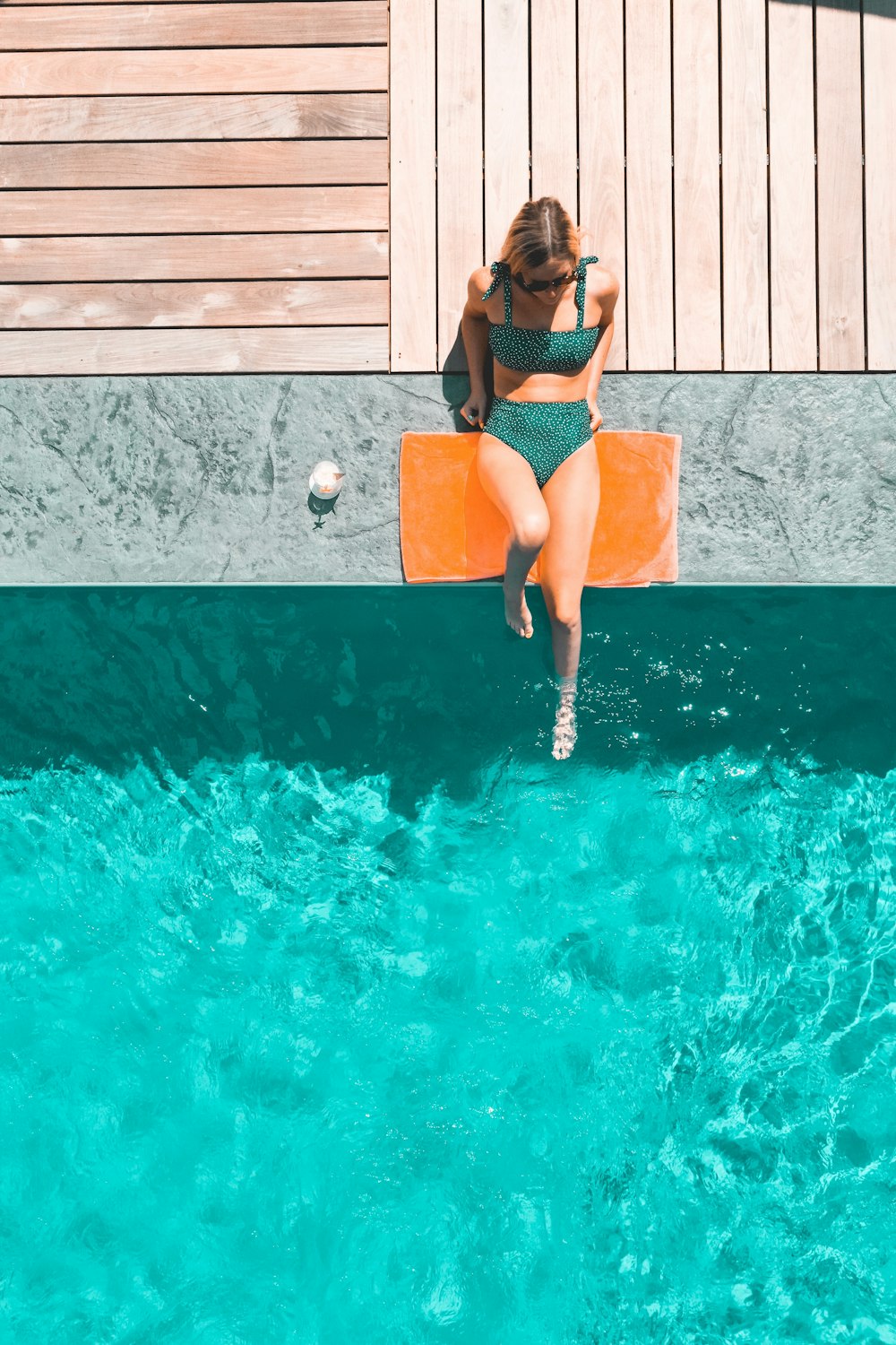 donna sdraiata accanto alla piscina durante il giorno