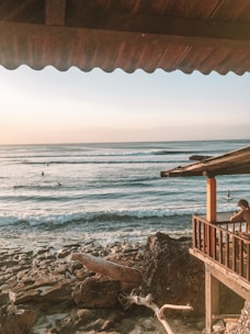 A cozy seaside porch with weathered wood and a view of crashing Atlantic waves at sunset.