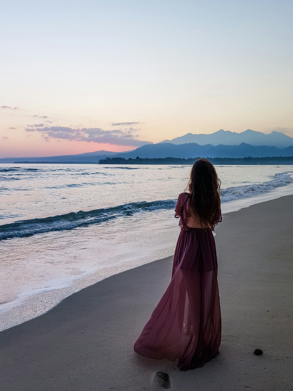 donna in piedi sulla riva del mare durante il giorno