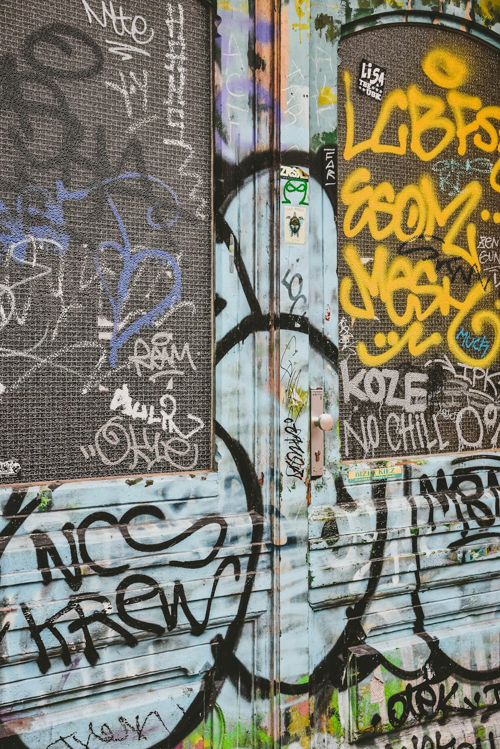 a wall covered in lots of graffiti next to a building