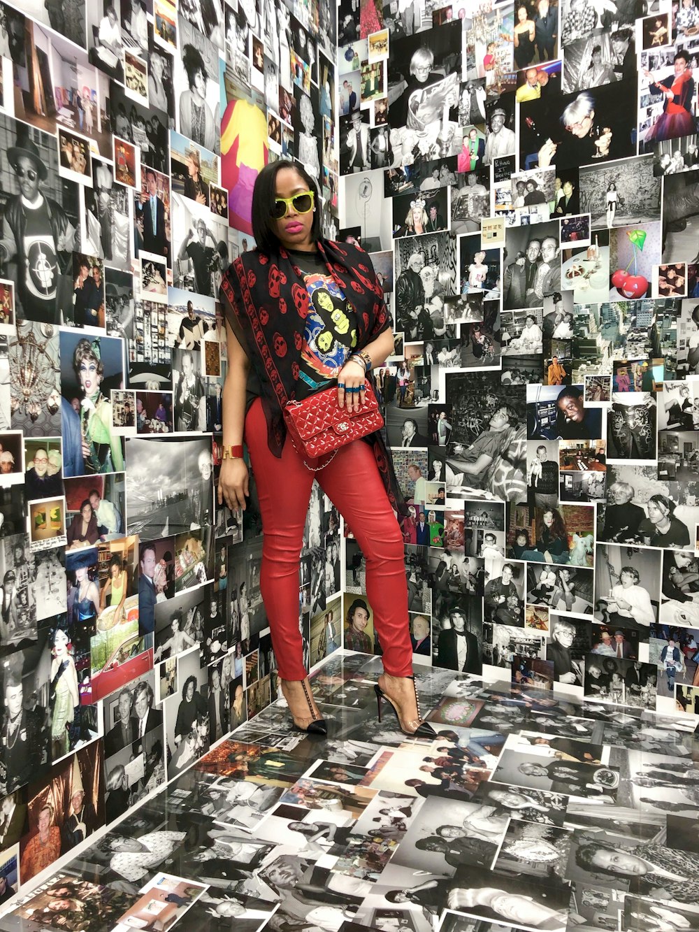 standing woman wearing red pants carrying bag inside room with photos