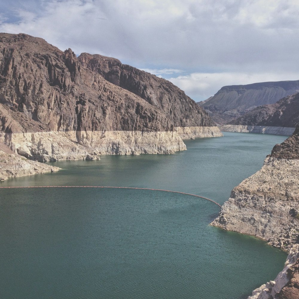 body of water between mountains under cloudy sky during daytime