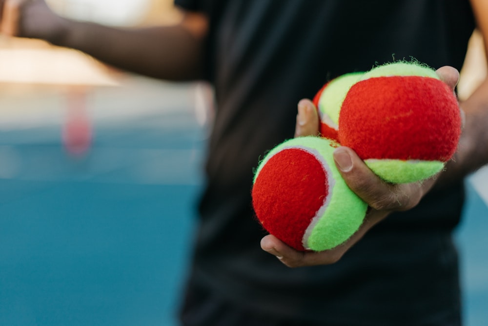 una persona sosteniendo dos pelotas de tenis en sus manos