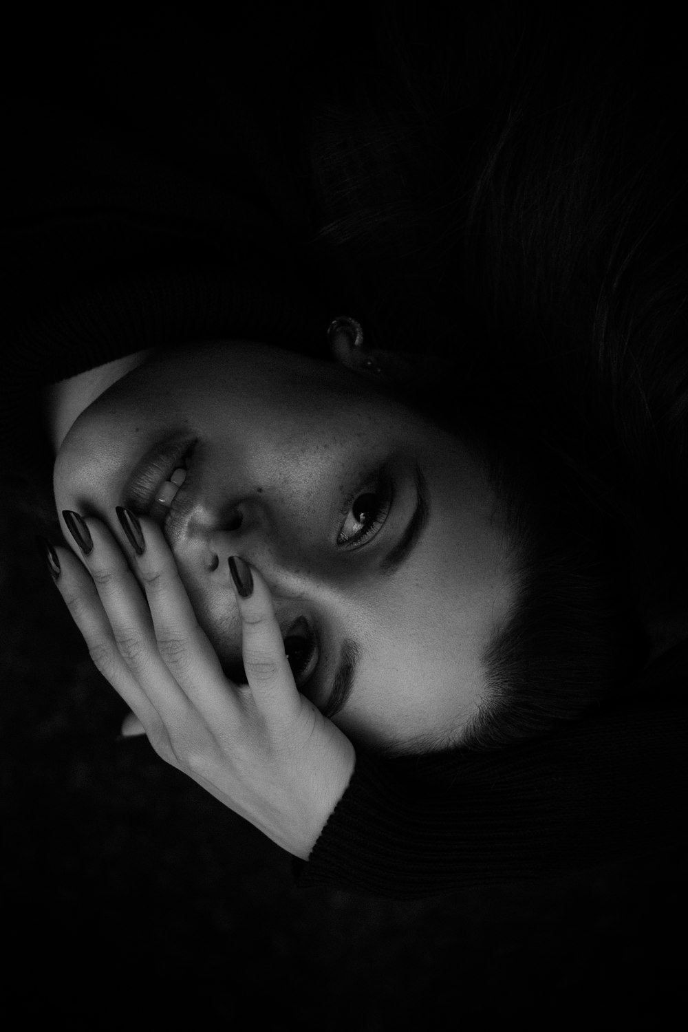 a black and white photo of a woman with her hands on her face