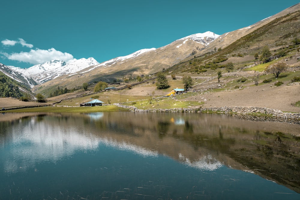 house field near body of water and mountains during day