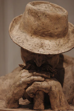 Traditional clay sculpture of a man with a hat and bag in natural light
