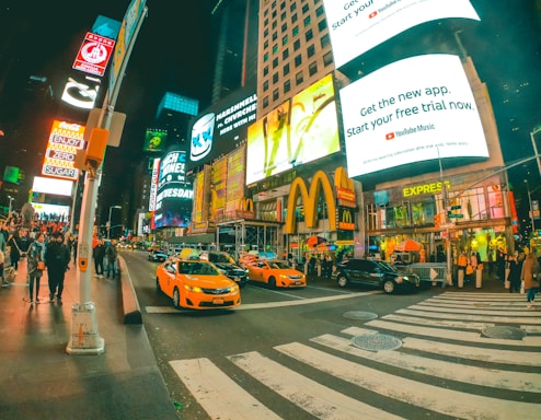 A vibrant photo of Times Square at night with bright billboards and a crowd gathered for a fashion event.