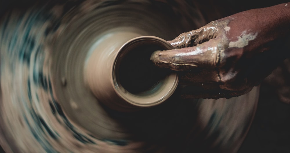 a potter's hand holding a pottery wheel