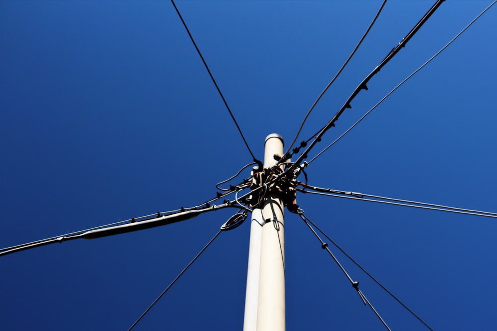 a white pole with wires and a blue sky in the background