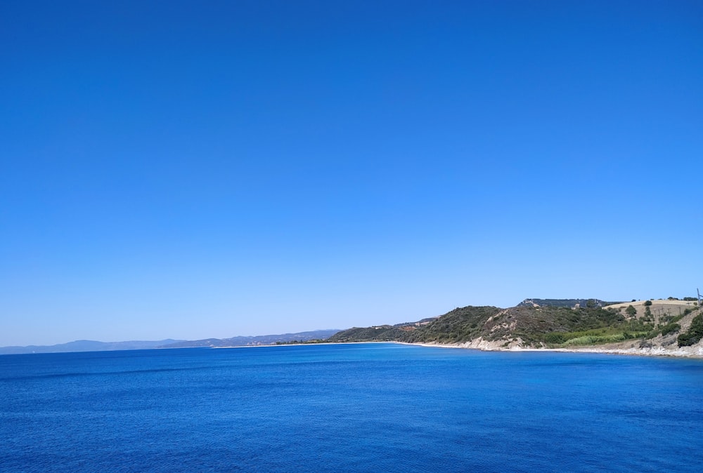 body of water near mountains at daytime