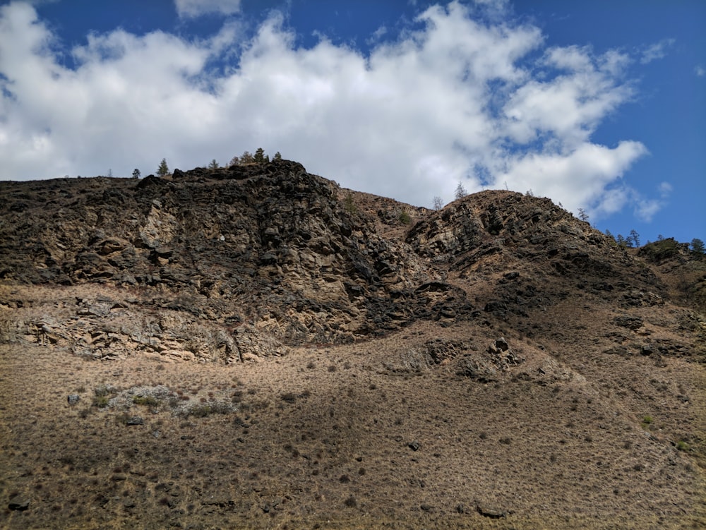 low-angle photography of brown mountain under a cloudy sky