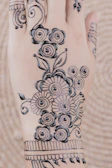 Intricate mehendi design on bride's hands showcasing fine, symmetrical patterns.