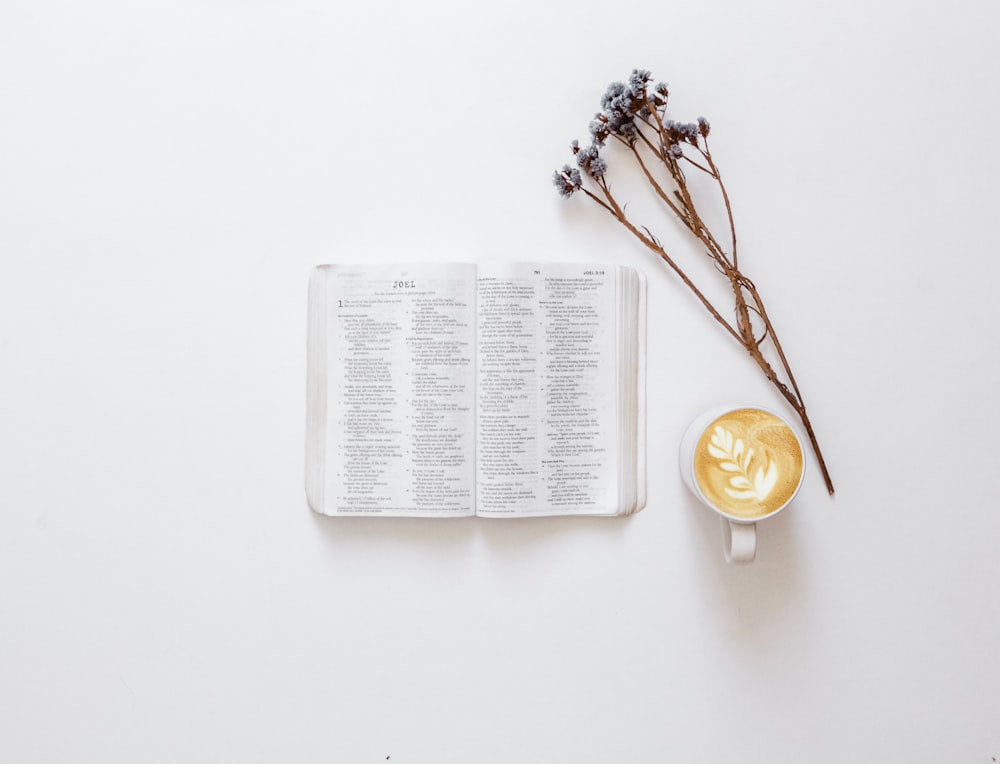 flatlay photo of Bible, flowers, and cup of latte