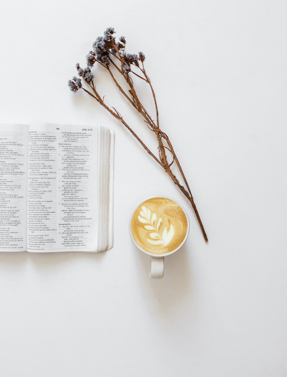 flatlay photo of flowers, bible, and cup of coffee latte
