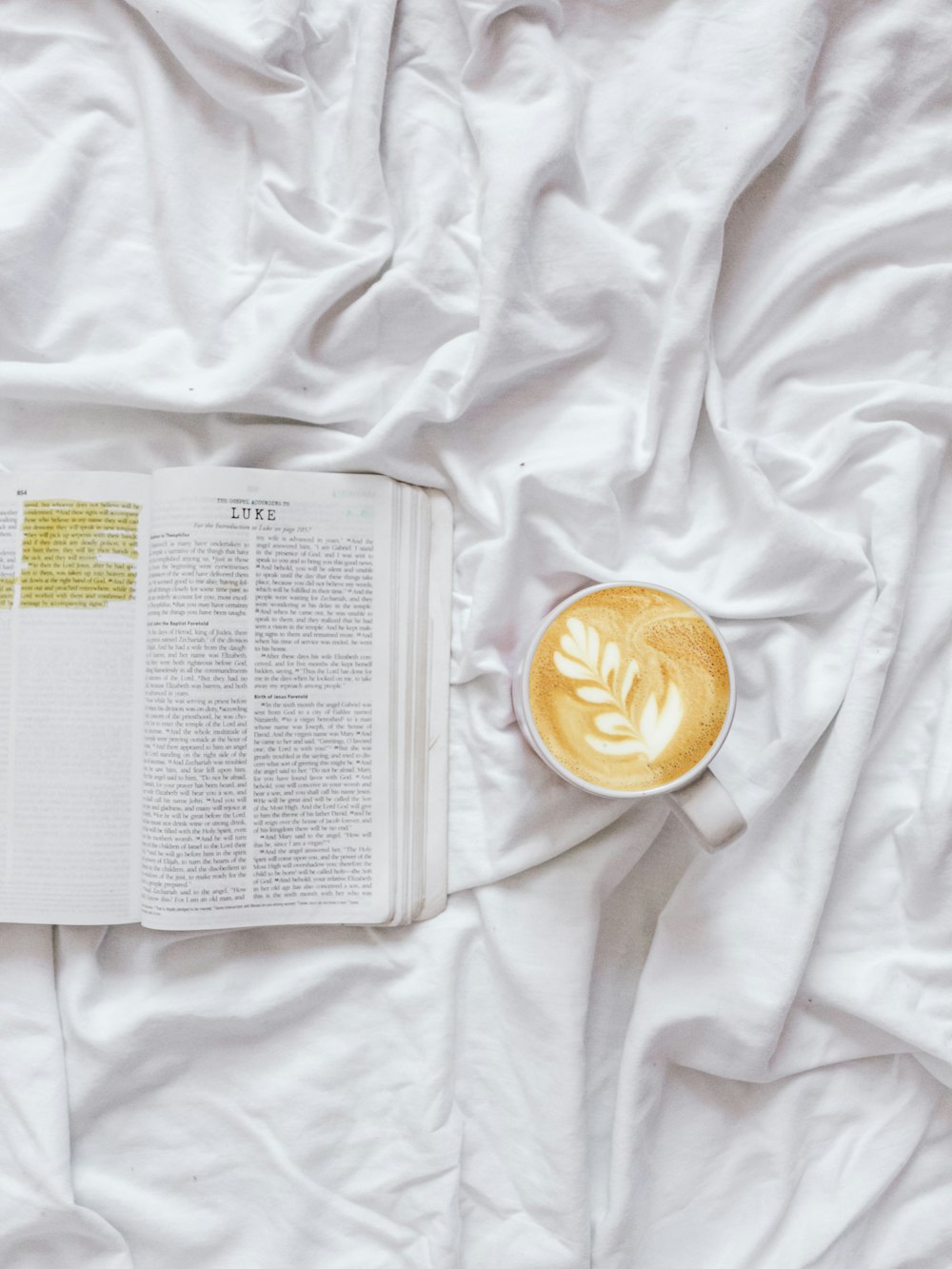 coffee on white blanket near paper