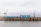 Photo of a busy industrial loading dock with trucks being loaded with coke under a steel-grey sky.