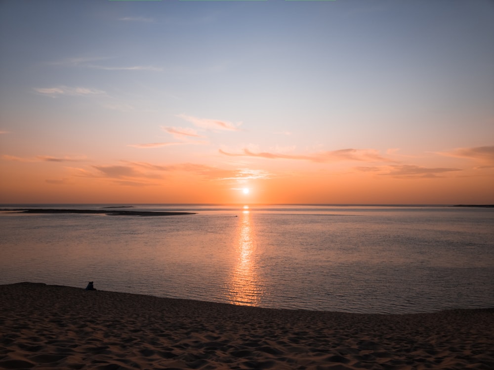 a person sitting on a beach watching the sun set