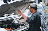 A mechanic inspecting a car's engine under the hood.