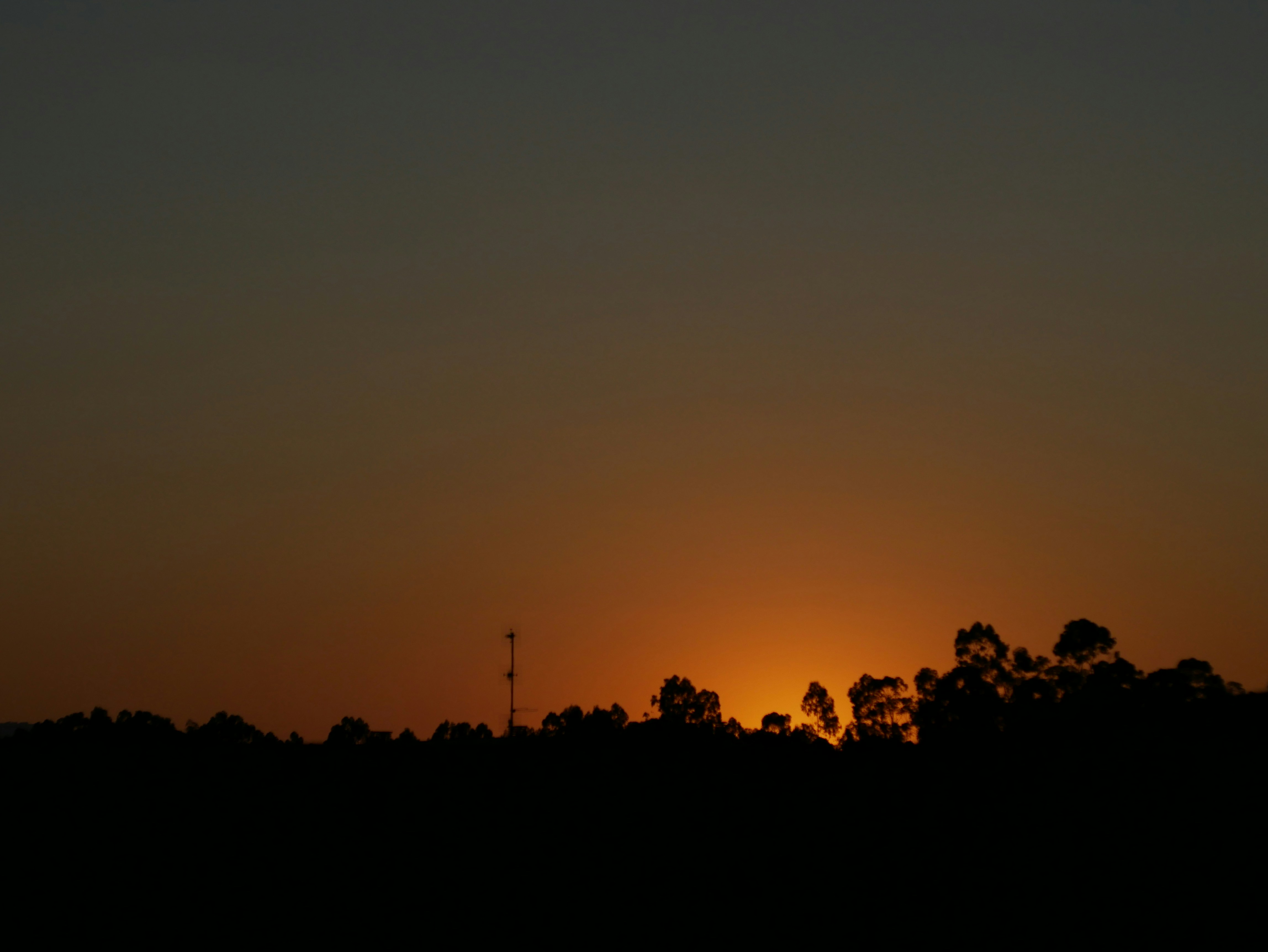 the sun is setting over the trees in the distance