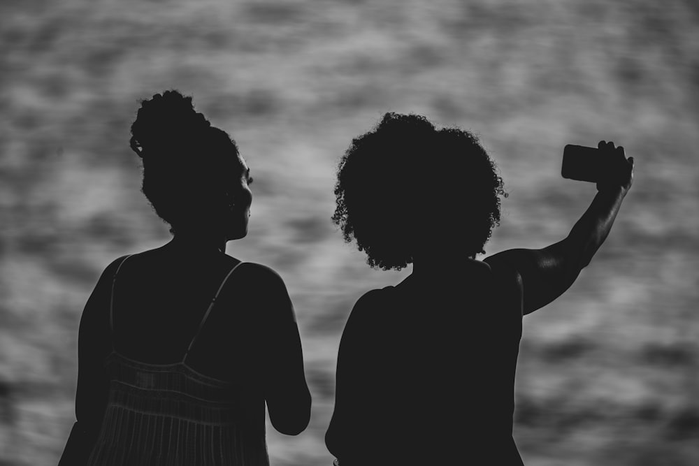 silhouette of two women near body of water