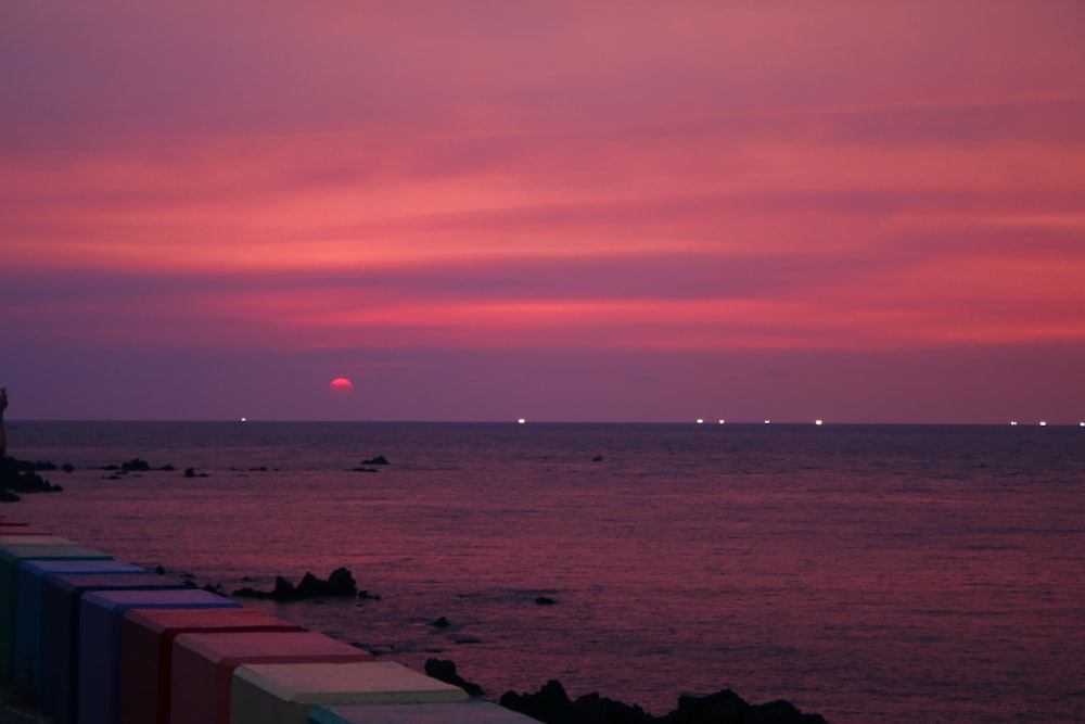 a sunset over a body of water with a lighthouse in the distance