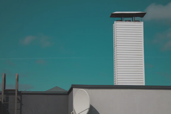 A friendly technician inspecting a chimney on a sunny Ventura rooftop.