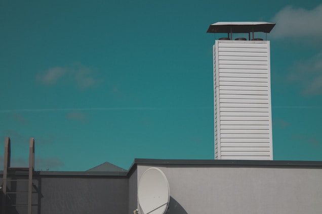Technician repairing a rooftop chimney under a bright Miami sky.