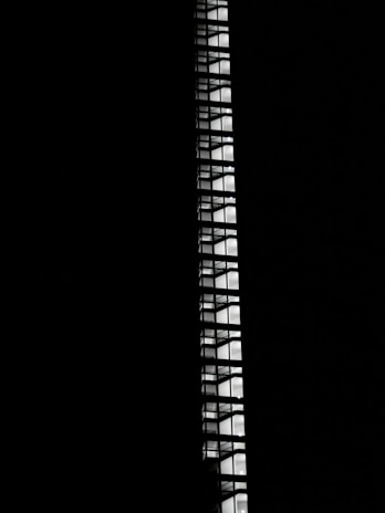 Pure black background featuring sleek, architectural lines in white and grey highlighting upward progress.