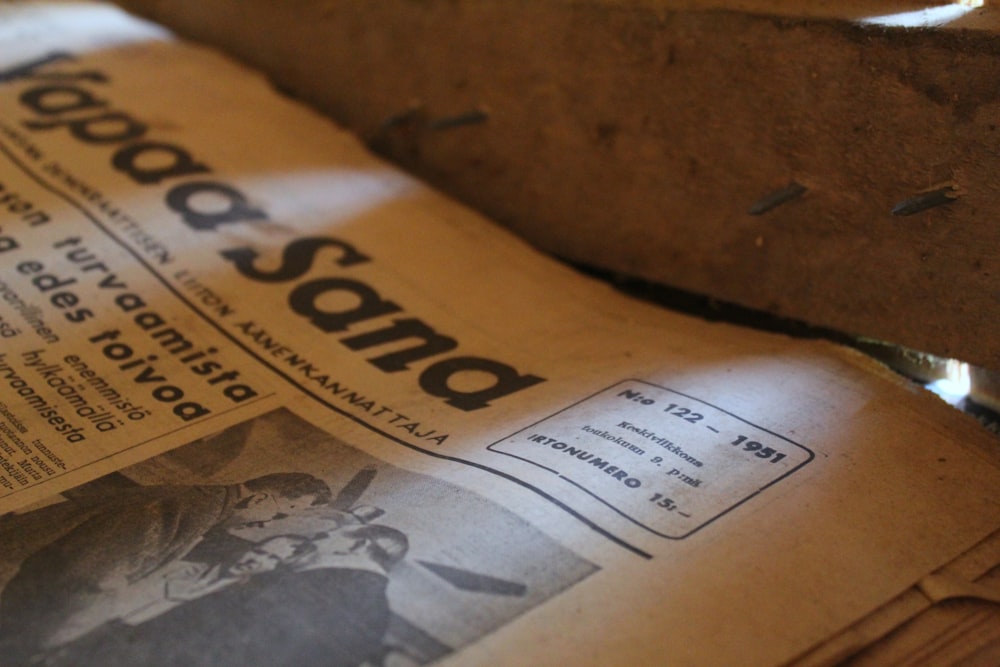 a pile of newspapers sitting on top of a wooden table