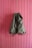 A green backpack hangs against a vertically paneled pink wooden wall. The backpack has leather straps and an overall rugged appearance, suggesting it is meant for outdoor use.
