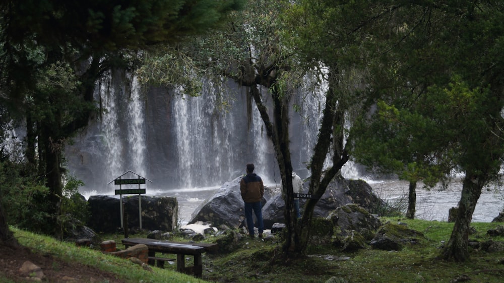 a man sitting on a bench in front of a waterfall