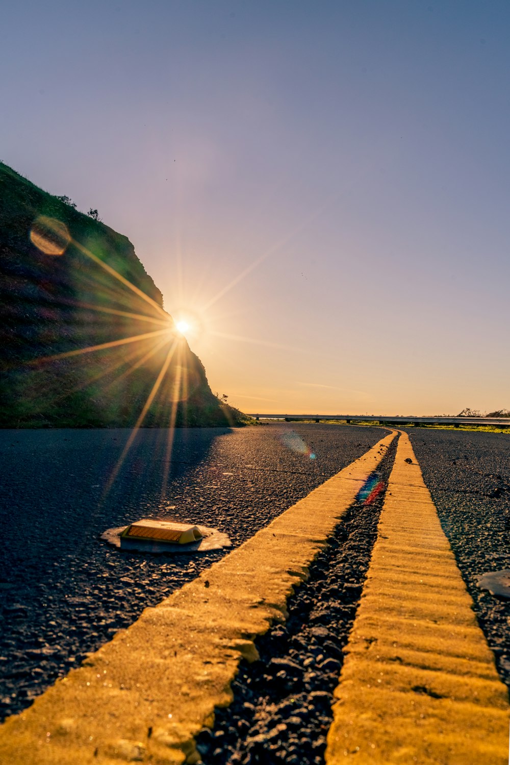 the sun is setting over a road with a yellow line
