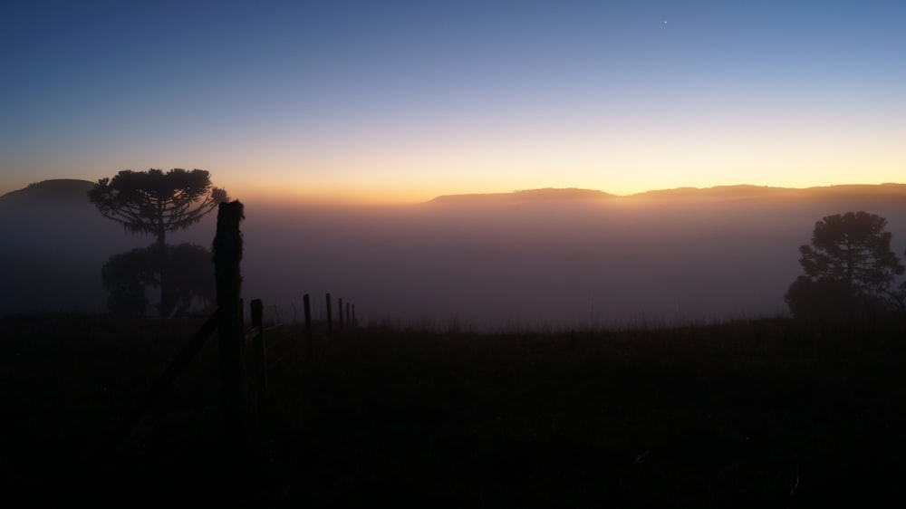 the sun is setting over a foggy valley