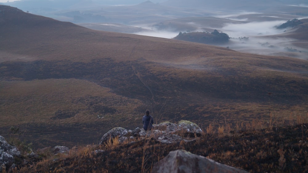 a man standing on top of a lush green hillside