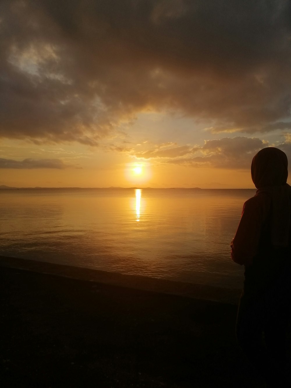 silhouette of person near body of water during golden hour