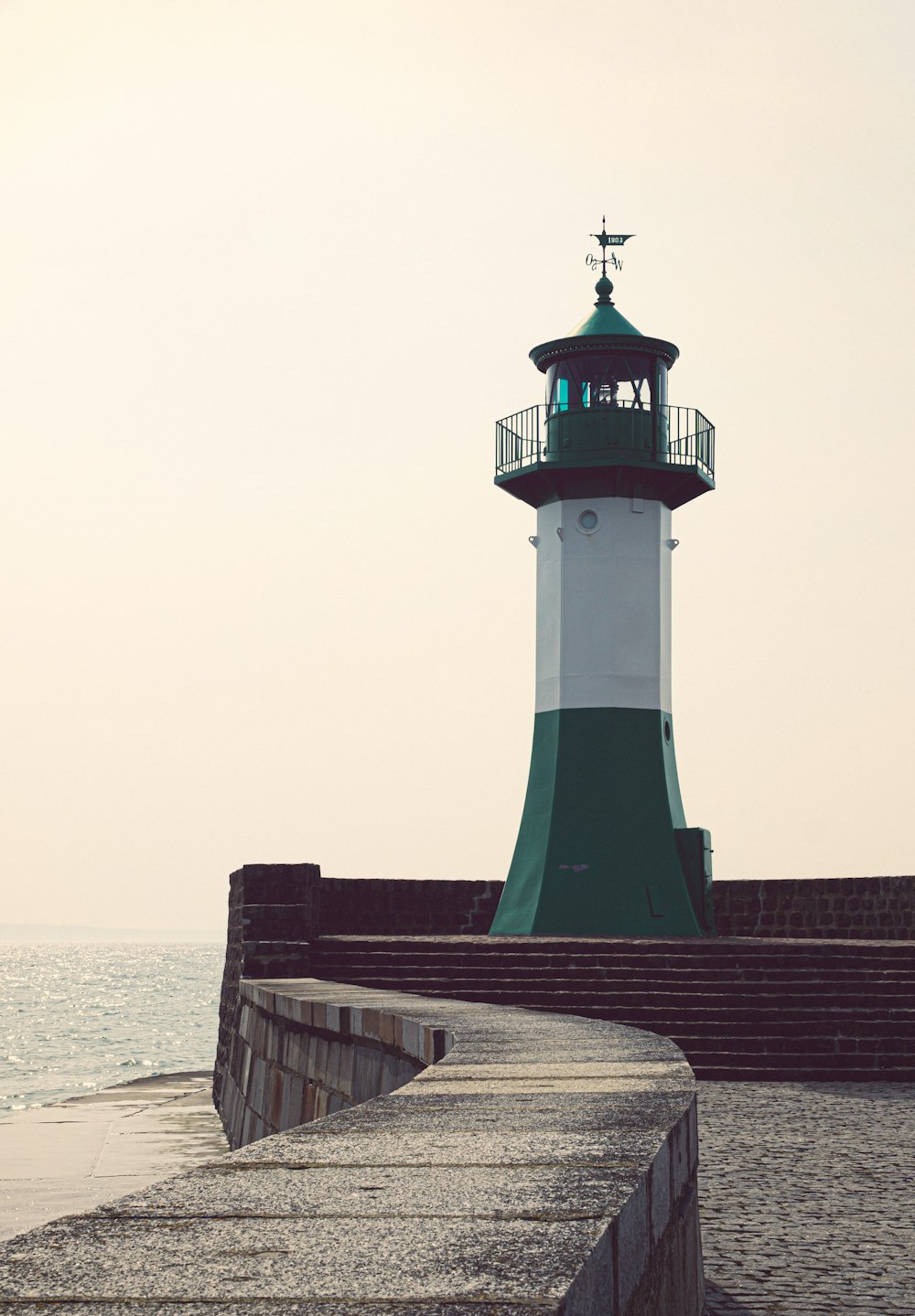 a green and white lighthouse sitting on top of a pier