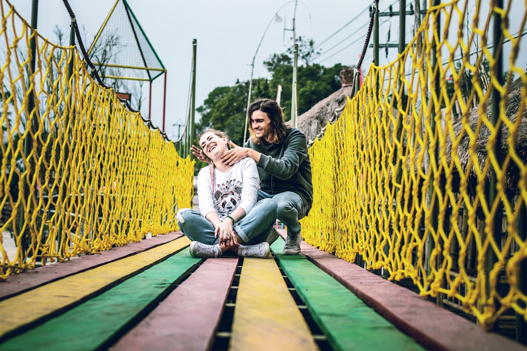 man and woman sitting on bridge