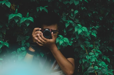 A photographer capturing a candid moment in a lush green outdoor setting.