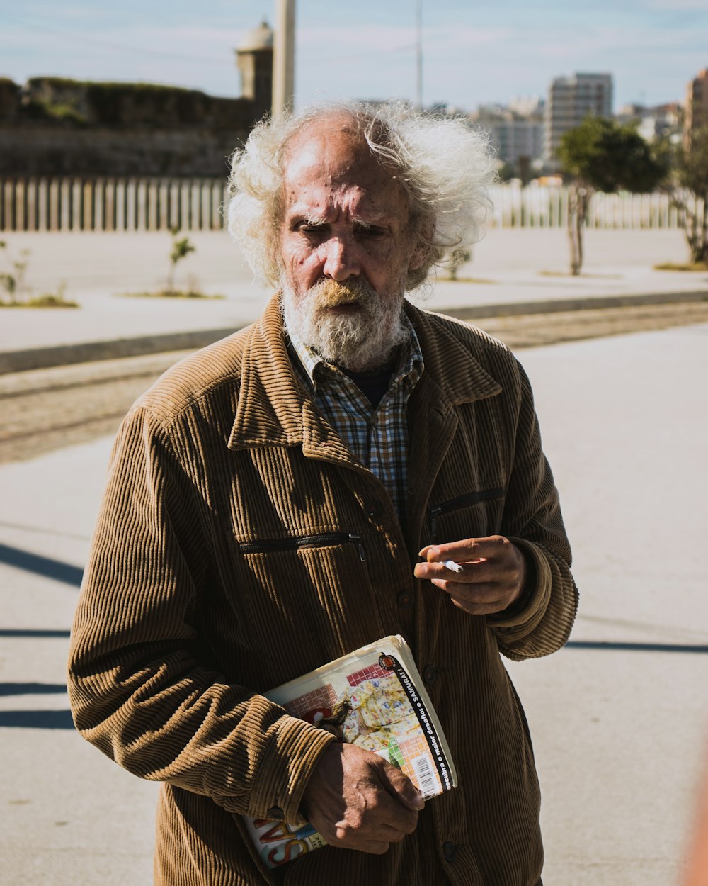 hombre con chaqueta abotonada marrón sosteniendo un libro