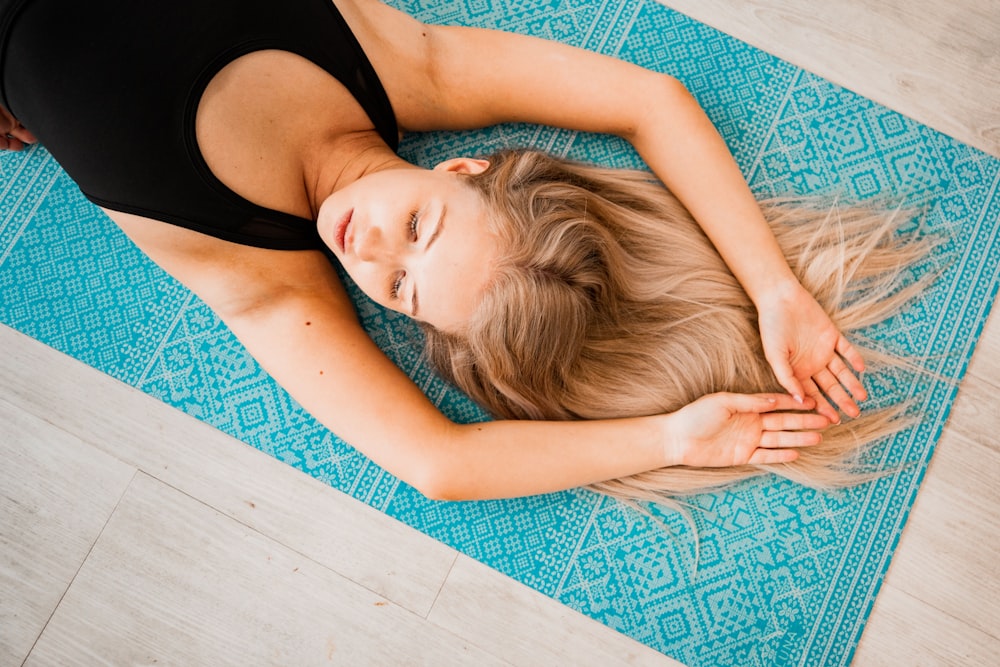 woman lying on teal mat