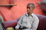 An older adult engaged in a calm coaching session at home, with soft blue and green decor in the background.
