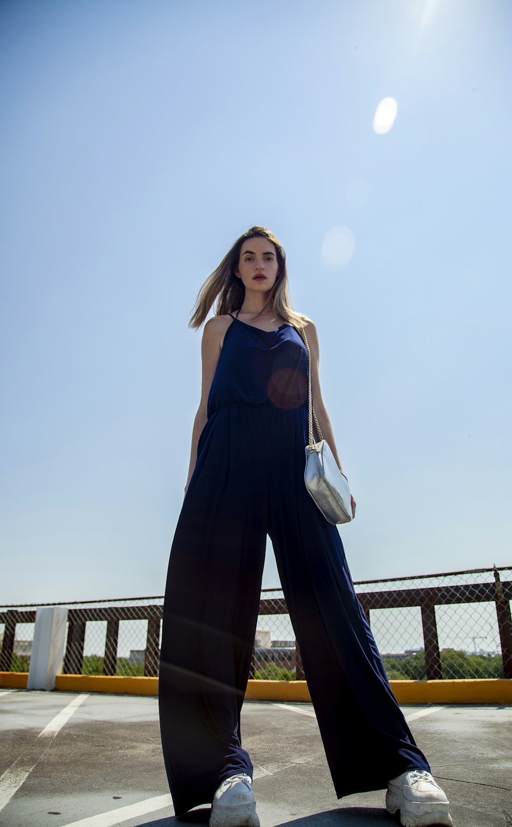 woman wears blue sleeveless jumpsuits and white sneakers