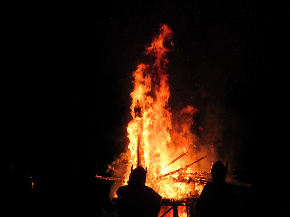 two persons facing bonfire