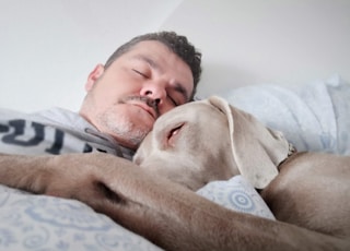 man laying on bed beside dog