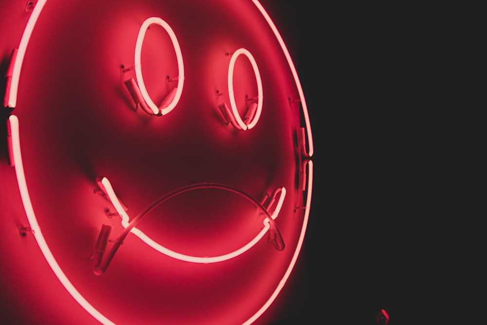 a red neon sign with a smiley face on it