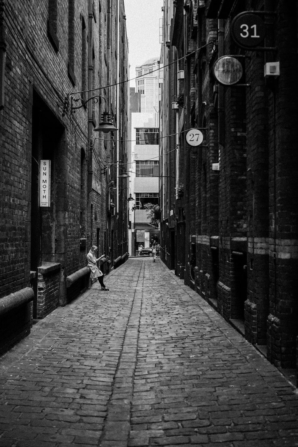 person leaning back on brick building in the alley