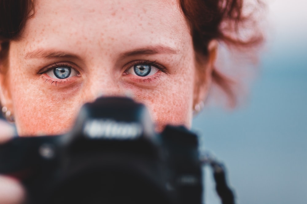 woman holding black Nikon camera