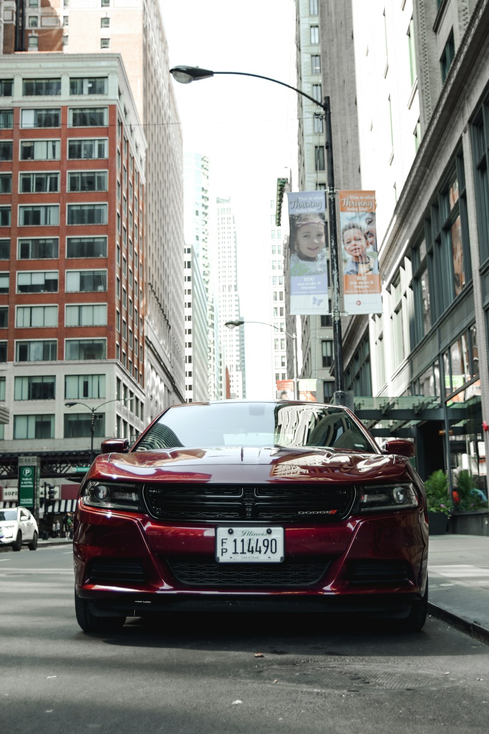 red vehicle parking near road beside high-rise buildings