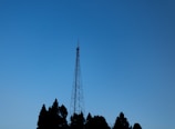 An outdoor FM antenna tower against a clear blue sky at sunrise.